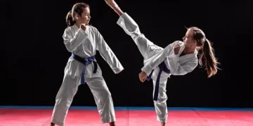 Two girls in taekwondo combat practicing martial arts. They wears kimonos