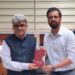 Satyarth Pandita presents his book to the Chief Secretary